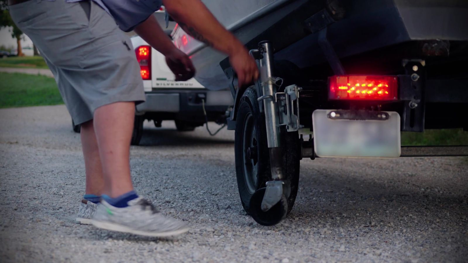 The Jack Bracket holding a loaded boat trailer up on a gravel lot while the owner works at the wheel