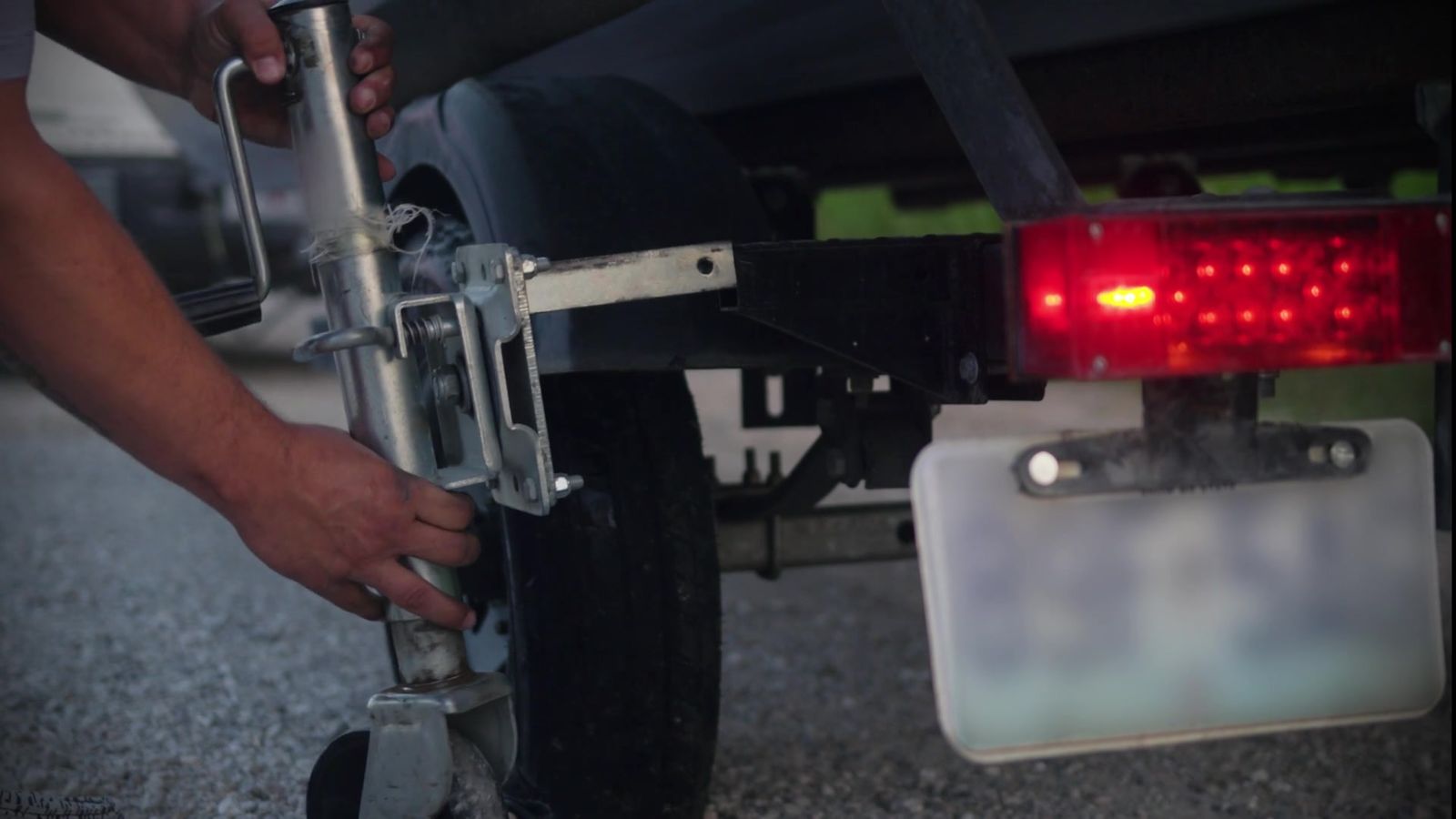 A factory trailer jack seated in the Jack Bracket axle receiver beside the rear wheel of a boat trailer